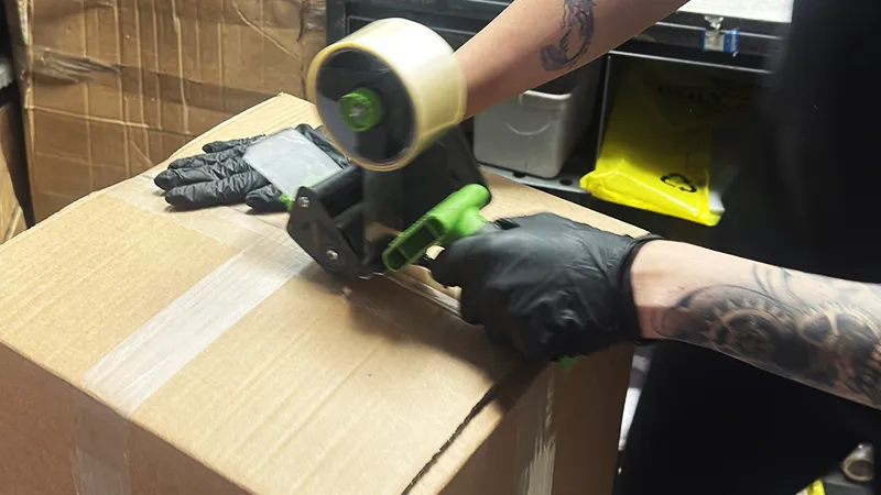 Hands closing a securely packed turbocharger box ready for delivery